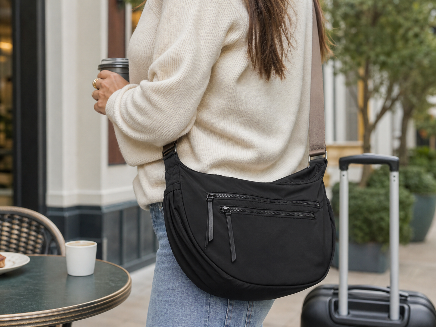 HoboPocket day bag worn beside a cafe table and travel suitcase